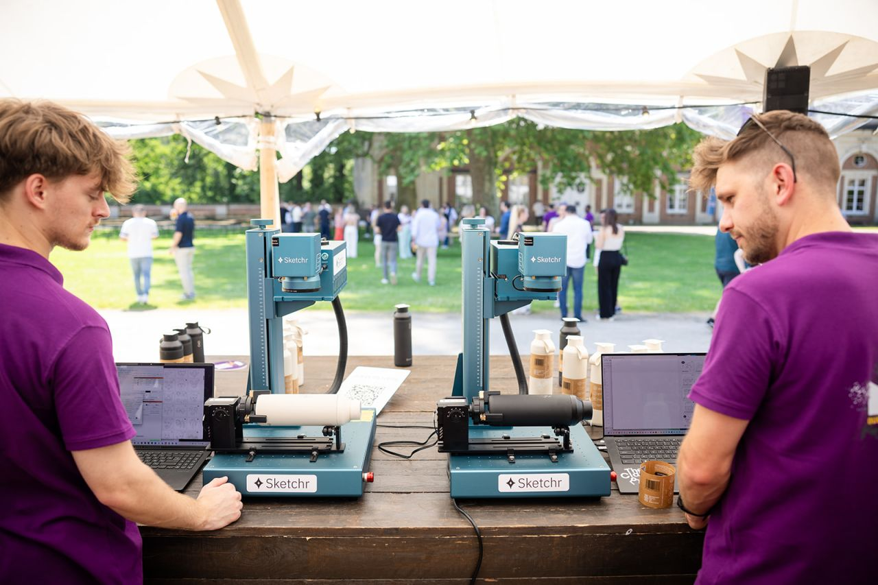 Twee lasermachines verwerken tegelijk gepersonaliseerde flessen tijdens de teambuilding